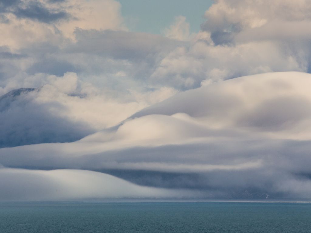 Perfectly Formed Domes of Cloud Covering the Mountains Near the Mouth of Glacier Bay AK wallpaper