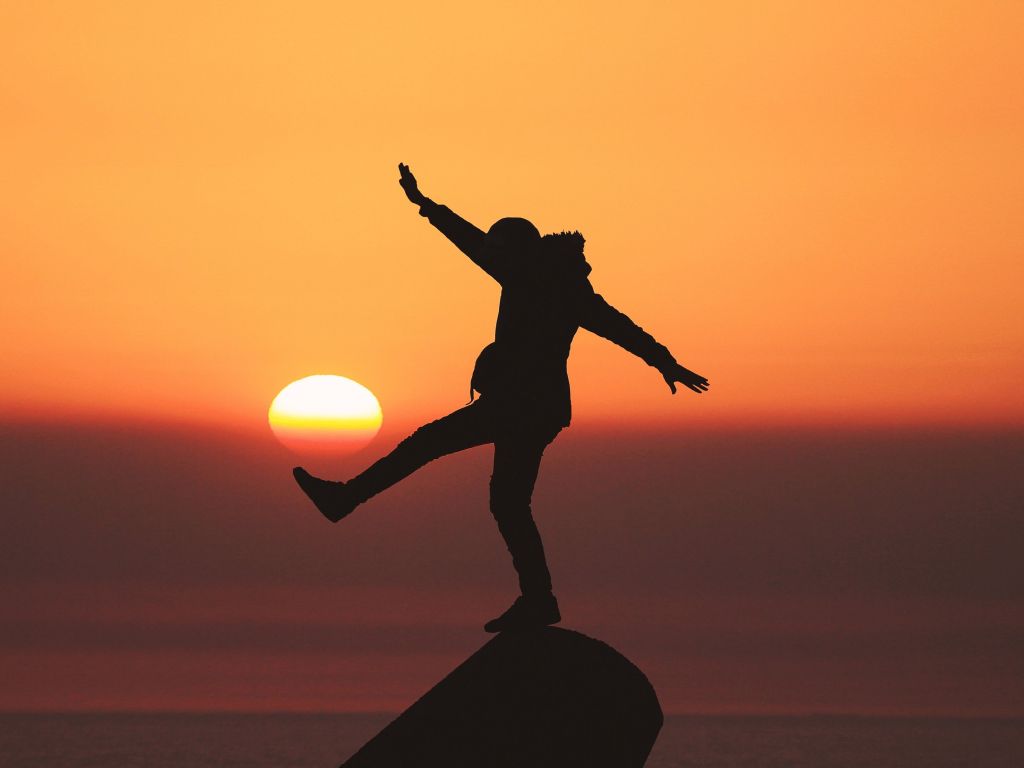 Photo of Silhouette Photo of Man Standing on Rock wallpaper