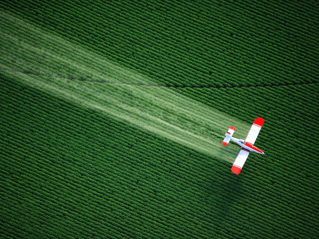 Plane Spraying Over Crop wallpaper